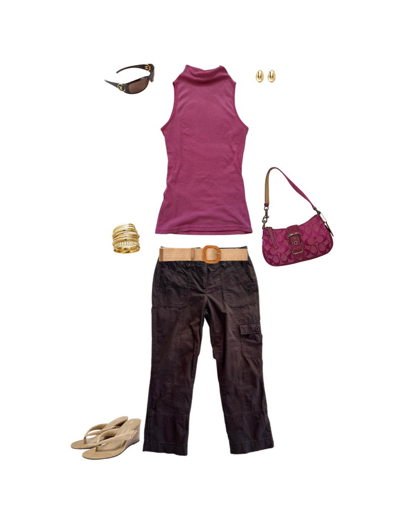 An outfit flat lay featuring a sleeveless magenta turtleneck top, dark brown pants, a tan belt, a matching magenta handbag, gold earrings, a gold bracelet, sunglasses, and beige sandals, all arranged on a plain white background.