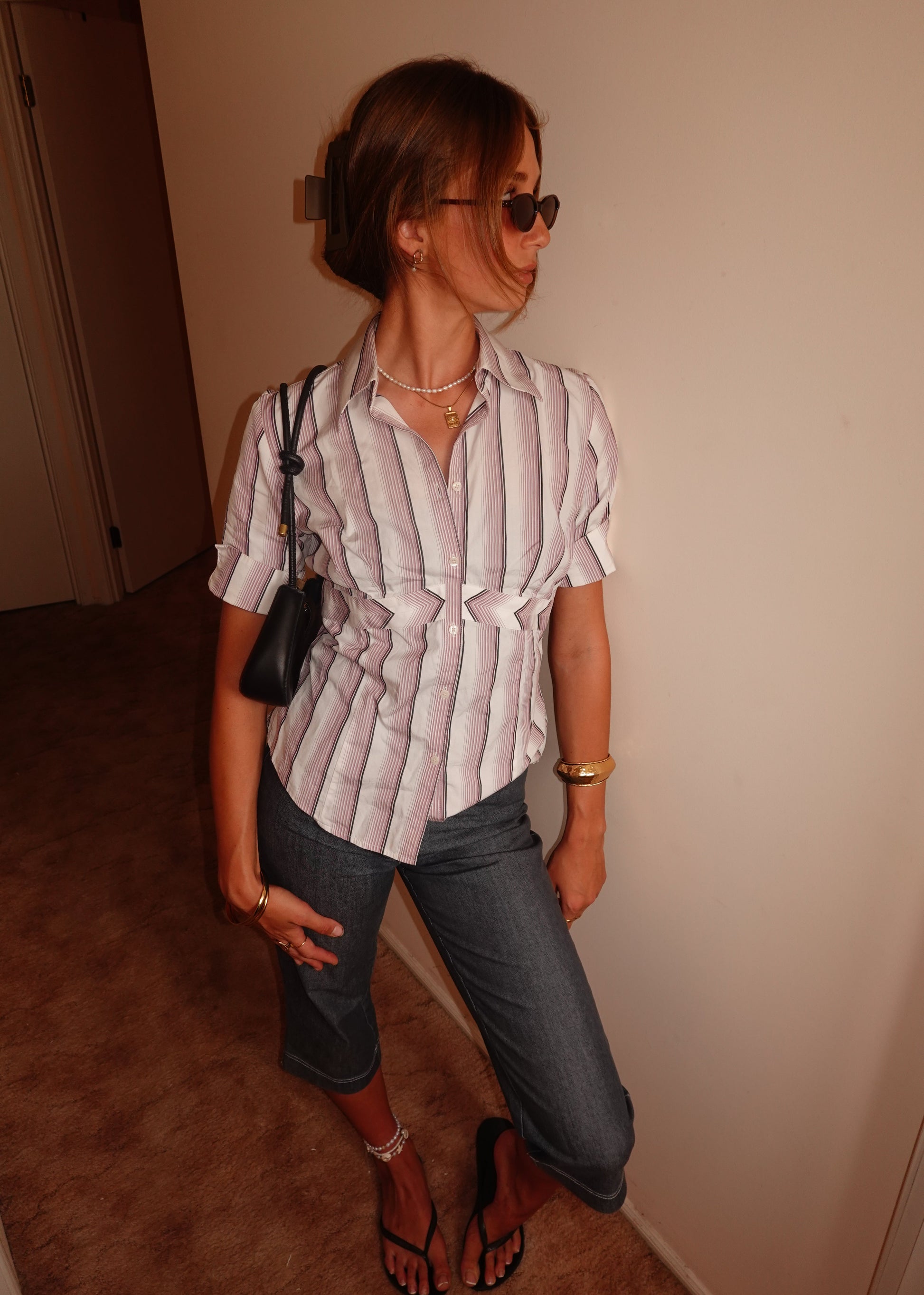 Person standing wearing the striped shirt with a neutral background.