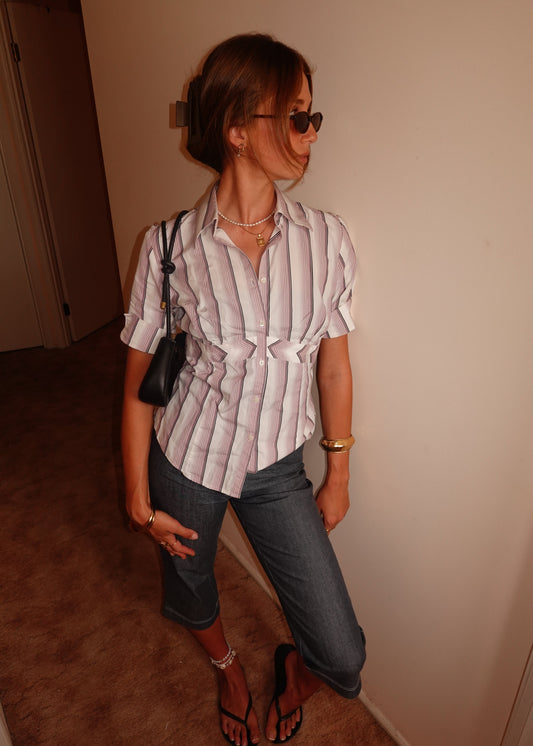 Person standing wearing the striped shirt with a neutral background.