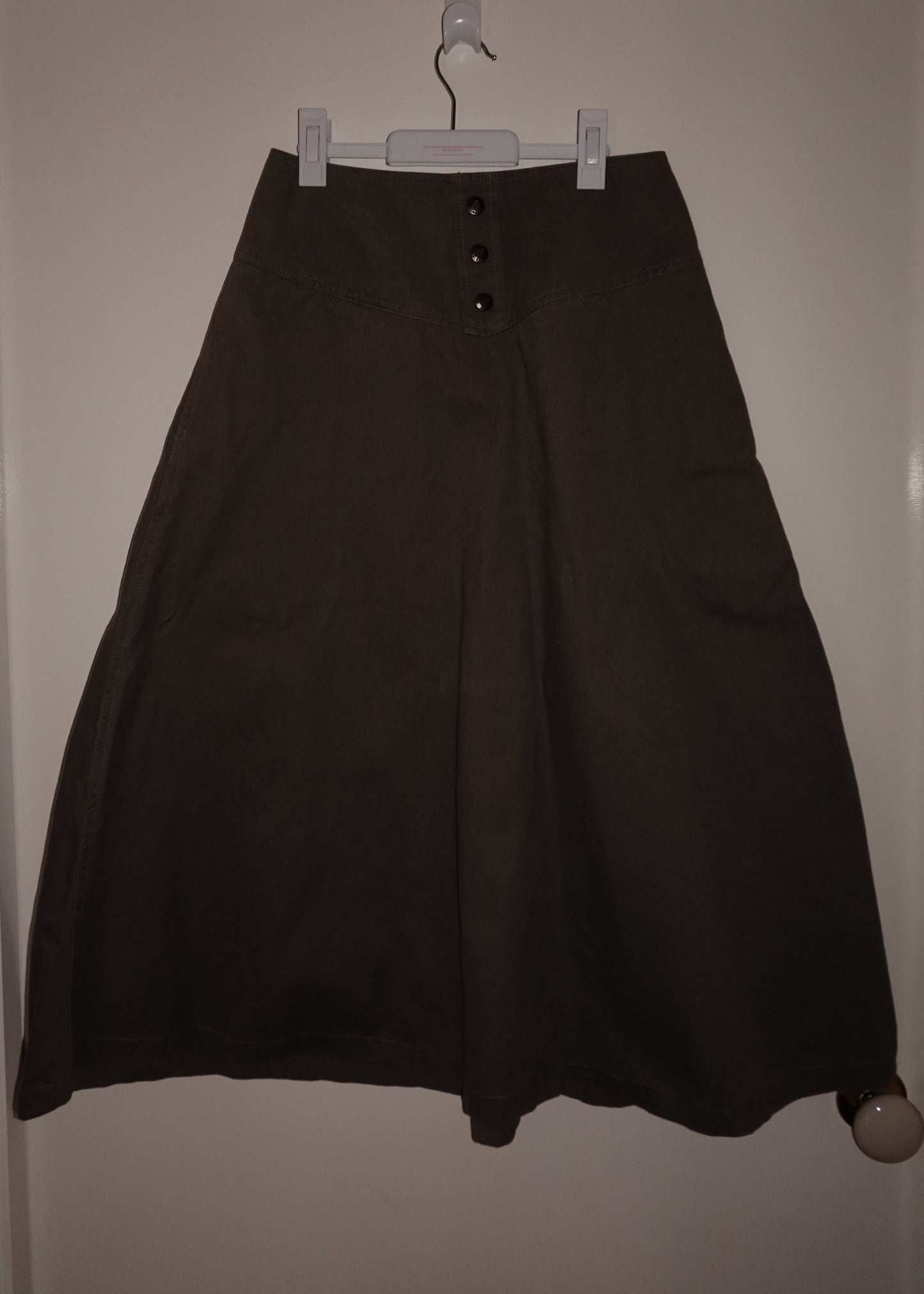 Black skirt hanging on a hanger against a white wall