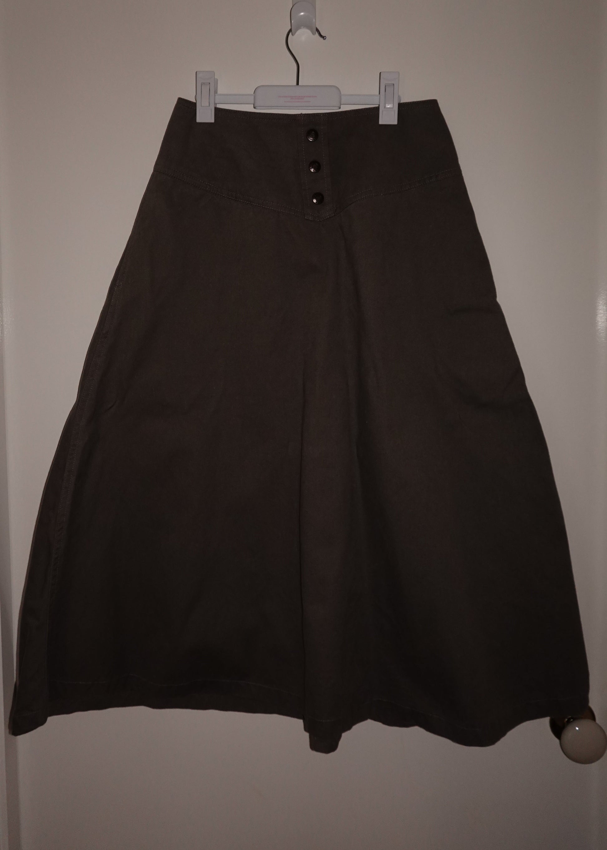 Black skirt hanging on a hanger against a white wall