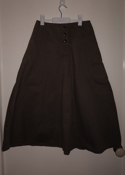 Black skirt hanging on a hanger against a white wall